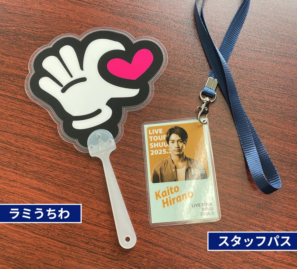 手形の白いラミネートうちわと、日本の男性アイドルの写真が入ったスタッフパスが並べて置かれている。